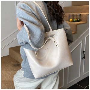 Detailed view of the creamy white tote bag featuring natural pleated texture and logo