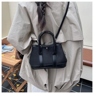 Detail view of the black tote bag showing premium canvas material and leather trim accents