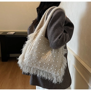 Detail of knit shoulder bag with pearl accents and fluffy feather fringe trim