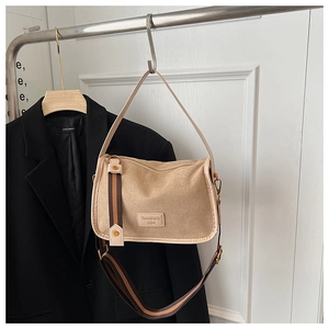 Detail of camel suede crossbody bag with wide striped strap and brand logo