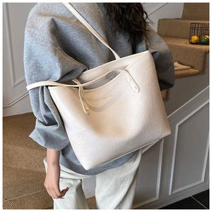 Close-up of cream white tote bag with gold logo and premium pleated leather texture