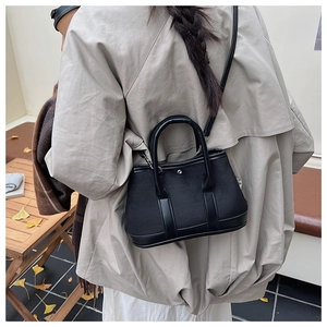 Detailed view of black canvas and leather crossbody bag in an autumn outdoor setting