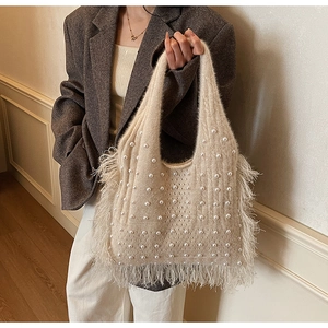 Detail of beige knitted handbag with faux fur texture, white pearls, and long fringe