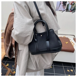 Close-up of black canvas and leather bag with metallic button on autumn street