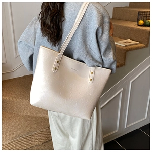 Detail view of large cream tote bag with wrinkled leather texture and gold studs