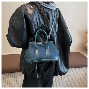 Detailed view of the dark teal suede bucket bag with metallic base studs and silver hardware