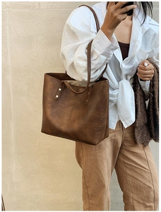 Close-up of vintage brown tote bag with leather texture and rivet detail on shoulder