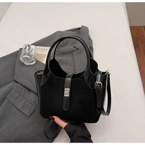 Detail of black matte and patent leather bucket bag with silver metal lock closure