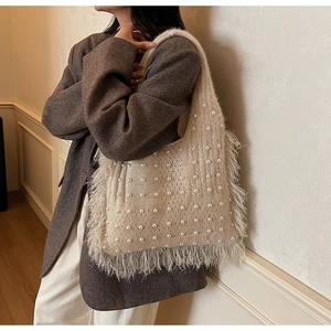 Detail view of beige knit tote bag with pearl accents and plush feather fringe trim