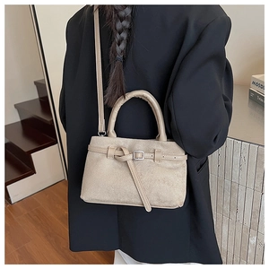 Detail of beige frosted crossbody bucket bag with decorative buckle on a black coat