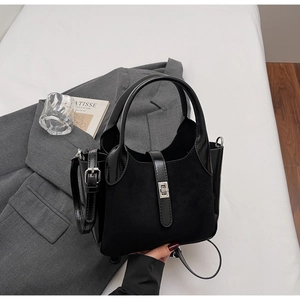 Detail of black crossbody bucket bag with suede paneling and silver turn-lock closure