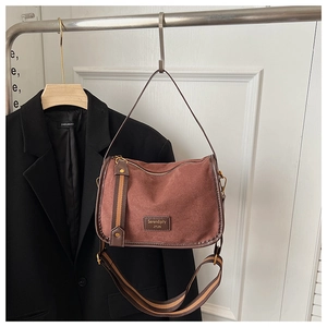 Detailed view of the brown suede crossbody bag with Serendipity label and striped strap