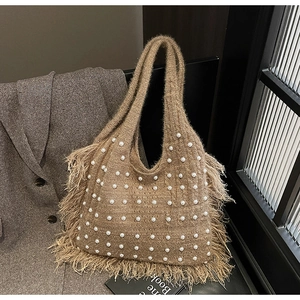 Detail of bohemian knitted tote bag with white pearl accents and long fringe tassels