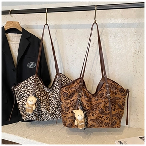 Detailed view of leopard and paisley tote bags with teddy bear charms on a rack