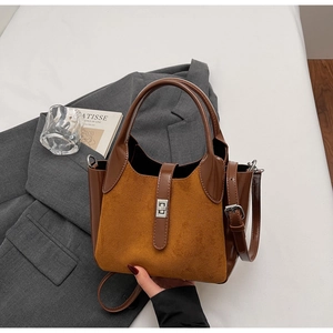 Detail of brown suede and leather bucket bag featuring a silver metal twist lock closure