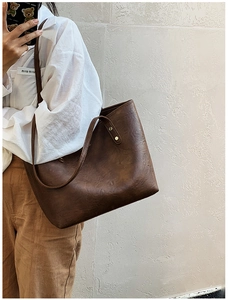 Close-up of retro brown tote bag featuring fine leather texture and gold rivet details