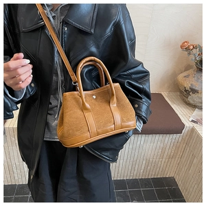 Close-up of vintage brown suede handbag with smooth leather trim and adjustable strap