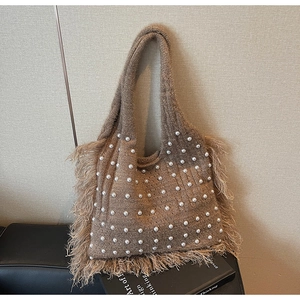 Detailed macro view of the brown knit tote bag with pearls and long fringe tassels