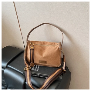 Close-up of brown suede crossbody bag with Serendipity logo and striped shoulder strap