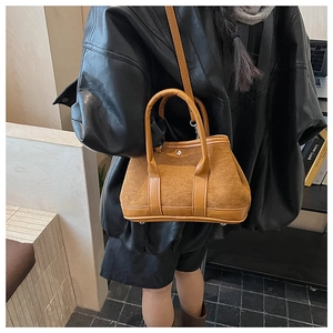 Brown suede crossbody bag with leather trim carried by a model in a leather jacket