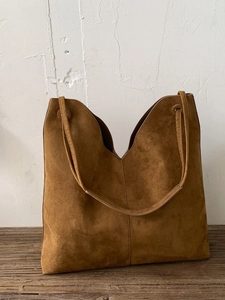 Vintage braune Wildleder-Einkaufstasche mit großem Fassungsvermögen auf Holztisch