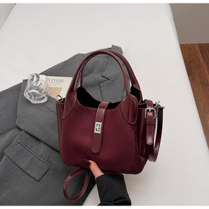 Detail view of burgundy matte suede bucket bag with silver clasp and leather strap