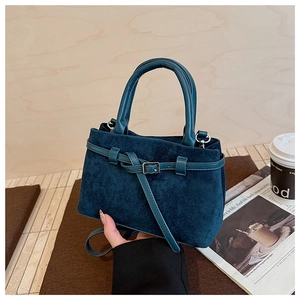 Close-up of deep teal frosted suede handbag with silver metal buckles and leather strap