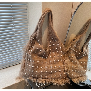 Close-up of brown knit tote bag with white faux pearl embellishments and fringe details