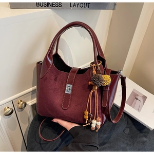 Close-up of burgundy frosted bucket bag with silver twist lock and bohemian tassel detail