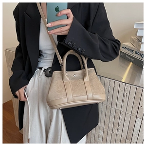 Close-up of khaki suede patchwork handbag with metal feet and shoulder strap details