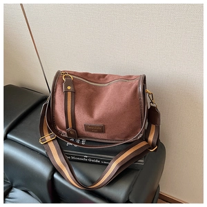 Close-up of brown suede saddle bag with Serendipity label and striped woven strap