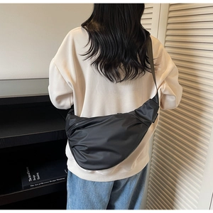 Detail of minimalist black nylon crescent crossbody bag with adjustable strap on model