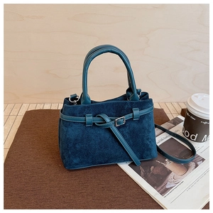 Detail of teal suede handbag with decorative leather strap and premium metal buckle