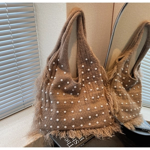 Detail of brown knit tote bag featuring white pearl embellishments and fringe trim
