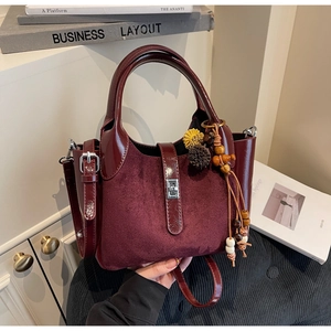 Detail of burgundy frosted suede and leather tote bag featuring a beaded tassel charm