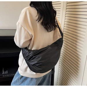 Minimalist black crescent crossbody bag shown in use on a model for daily commuting