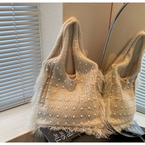 Detail of beige knitted tote bag featuring elegant pearl beads and soft feather fringe