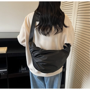 Detail of black crescent crossbody bag with pleated nylon fabric and wide strap