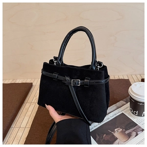 Close-up of black faux fur crossbody bucket bag with smooth leather handle and metal buckle