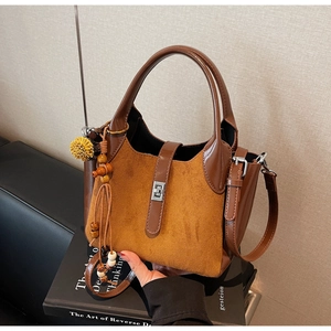 Detail of two-tone brown bucket bag with suede texture and wooden bead pendant accessory