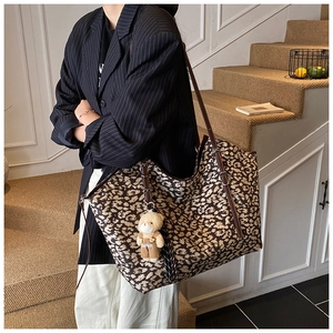 Detail of leopard print tote bag with leather straps and a cute teddy bear pendant