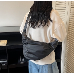 Rear view of model wearing minimalist black nylon crescent sling bag with adjustable strap