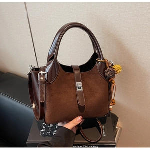 Detail of vintage brown bucket bag with mixed leather texture and wooden bead charm