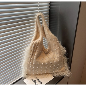 Close-up of beige knitted tote bag with elegant pearls and fluffy feather fringe trim