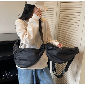 Close-up of black crescent nylon shoulder bag with adjustable wide strap on model