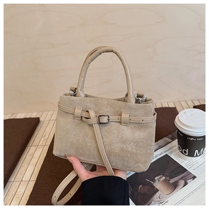 Detailed close-up of light brown matte suede bucket bag with stylish leather straps