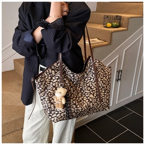 Close-up of leopard print tote bag featuring a cute brown bear charm and slim handles