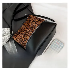 Detailed close-up of mixed black leather and leopard print plush tote with wide strap