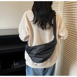 Close-up of black nylon dumpling crossbody bag showing textured water-resistant fabric