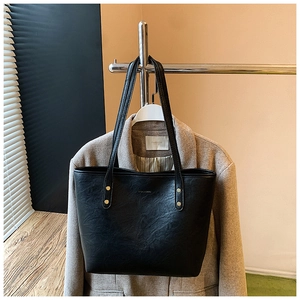 Detail of black tote bag with vintage leather texture and gold metal rivet accents
